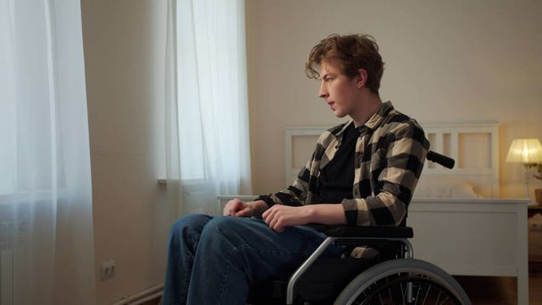 Un jeune handicapé roule dans son fauteuil roulant autour de la chambre - Photo, image