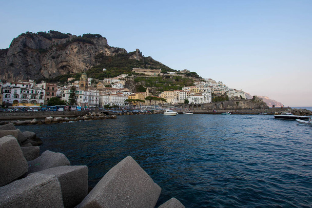 AMalfi, Włochy: 03 kwiecień 2019: Panoramiczny widok na piękne Amalfi na wzgórzach prowadzących do wybrzeża, Kampania, Włochy. Wybrzeże Amalfi jest najbardziej popularnym miejscem podróży i wypoczynku w Europie - Zdjęcie, obraz