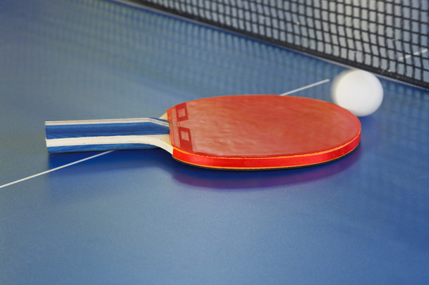 red racket, tennis ball on blue ping pong table - Photo, image