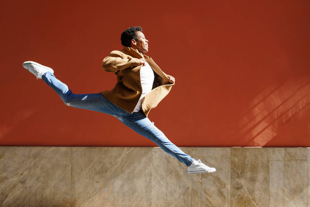 Šťastný černoch dělá akrobatický skok uprostřed ulice. - Fotografie, Obrázek