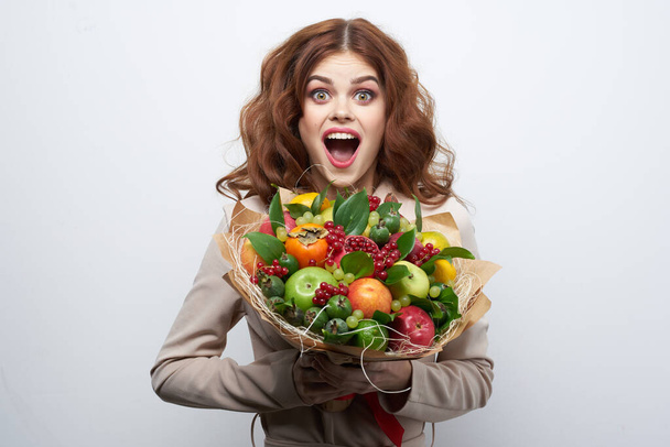 pretty woman bright makeup attractive look a bouquet of fruits light background - Foto, Imagen