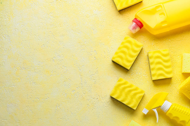 Sárga tisztító szivacs és üveg mosószer színes háttér - Fotó, kép