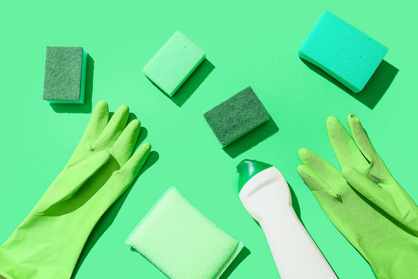 緑のクリーニングスポンジ、手袋、カラー背景に洗剤のボトル - 写真・画像