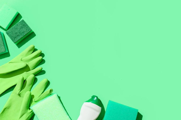 Esponjas de limpieza verde, guantes y botella de detergente sobre fondo de color - Foto, Imagen