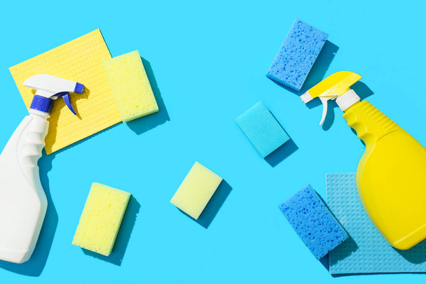 Esponjas de limpeza, trapos e garrafas de detergente sobre fundo azul - Foto, Imagem