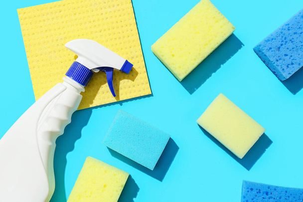 Cleaning sponges, rag and bottle of detergent on blue background - Foto, Imagem