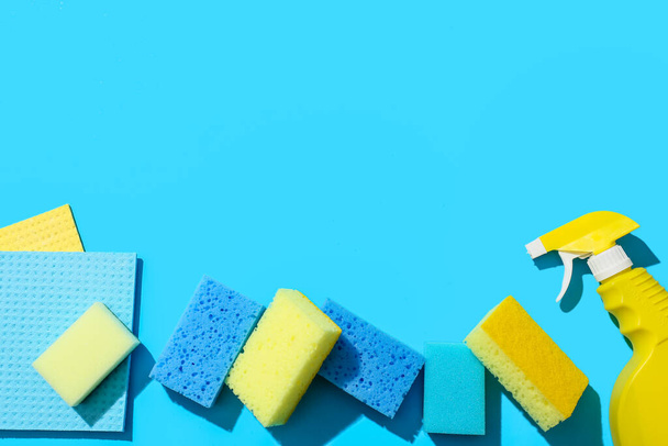 Cleaning sponges, rag and bottle of detergent on blue background - Photo, Image