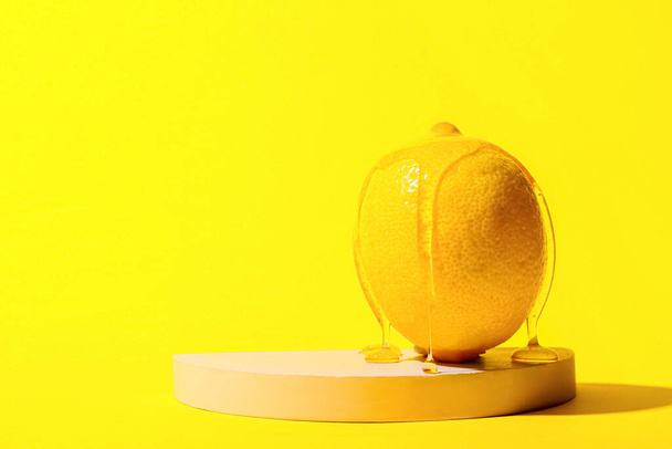Honey flowing down from lemon on color background - Photo, Image