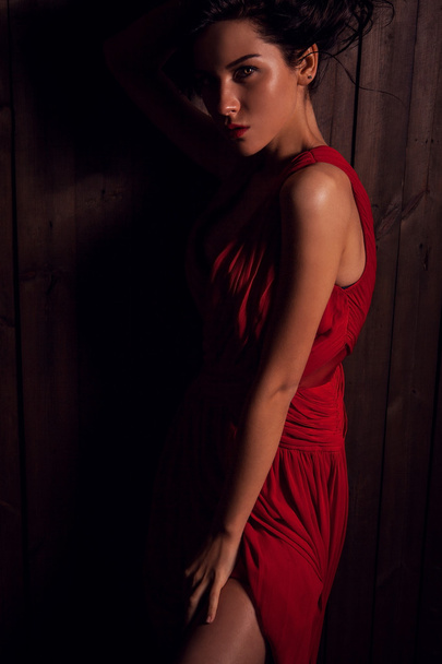 Lady in red pose on wooden background. Close-up photo. - 写真・画像