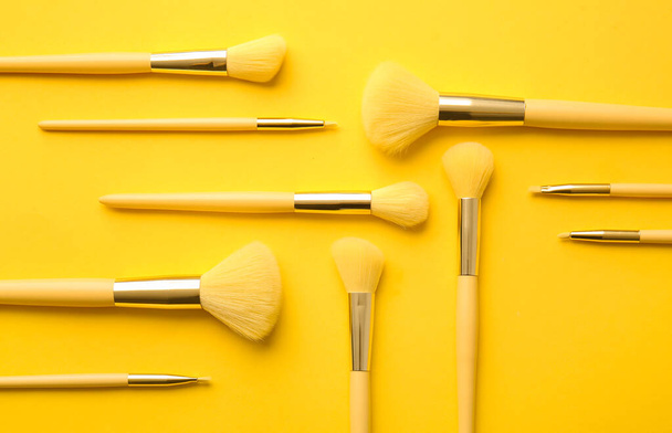 Set de elegantes pinceles de maquillaje sobre fondo amarillo - Foto, imagen