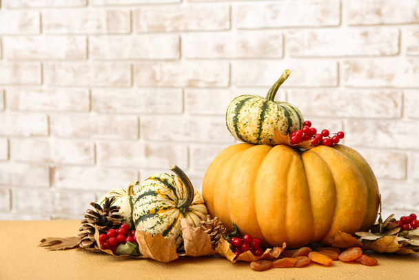 Composition d'automne festive avec des citrouilles sur la table contre le mur de briques - Photo, image