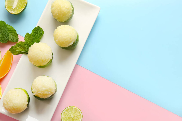 Plaat met lekkere ijsjes in limoenschilletjes op kleur achtergrond - Foto, afbeelding