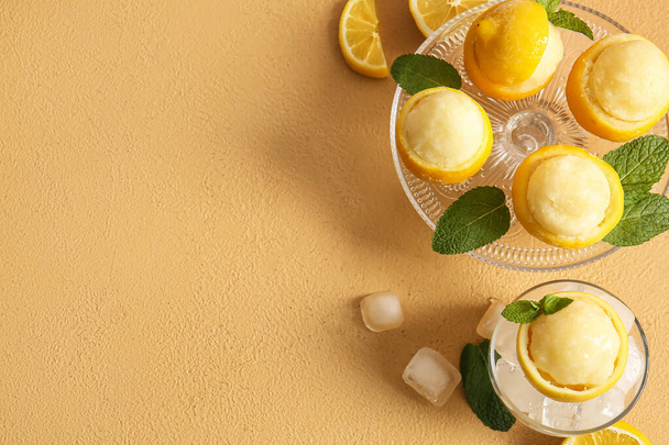 Dessertstandaard met lekkere ijsjes in citroenschil op kleur achtergrond - Foto, afbeelding