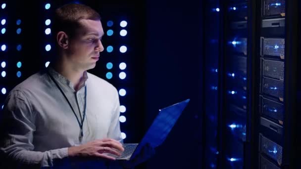 Il concetto di digitalizzazione delle informazioni: Specialista IT in piedi di fronte a rack server con computer portatile, Attiva il data center con un gesto touch. Dati di rete - Filmati, video