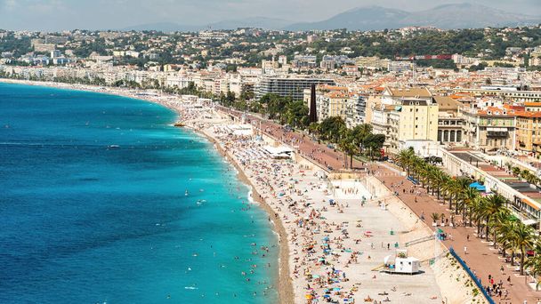 Uitzicht op de Côte d 'Azur in Nice, Frankrijk. Meervoudige rust op het strand mensen, gebouwen, blauw water van de Middellandse Zee - Foto, afbeelding