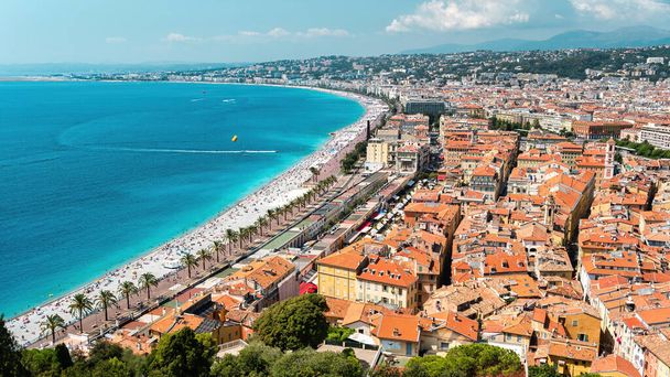 Vue sur la cote d'Azur à Nice, France. Repos multiples sur la plage personnes, bâtiments, eau bleue de la mer Méditerranée, collines sur le fond - Photo, image