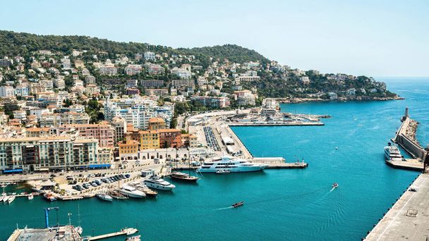 Вид на порт в Ницце, Франция. Несколько пришвартованных катеров и яхт, здания и зеленые насаждения, голубая вода Средиземного моря - Фото, изображение