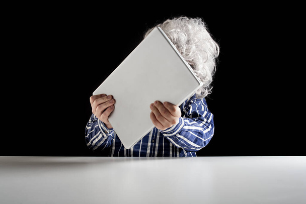 An elderly man does not know how to use the computer. He holds the laptop in his hand without knowing how to turn it on  - Photo, image