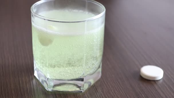 Effervescent yellow tablet dissolves in a transparent glass with water - Footage, Video