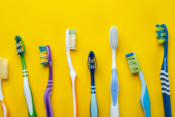 Toothbrushes on yellow background. Hygiene of the oral cavity. Top view. - Photo, Image