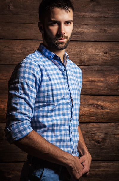 Portrait of young beautiful fashionable man against wooden wall. - Photo, Image
