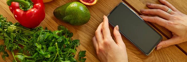 Banner Woman is using digital tablet or smarthone, looking recipe cooking in the kitchen at home, Healthy food concept, vegan or diet. Grocery online shopping - 写真・画像