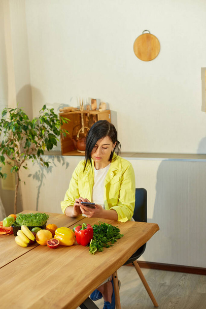 Donna sta usando tablet digitale o smarthone, cercando cucina ricetta in cucina a casa, concetto di cibo sano, vegan o dieta. Negozi online di alimentari - Foto, immagini