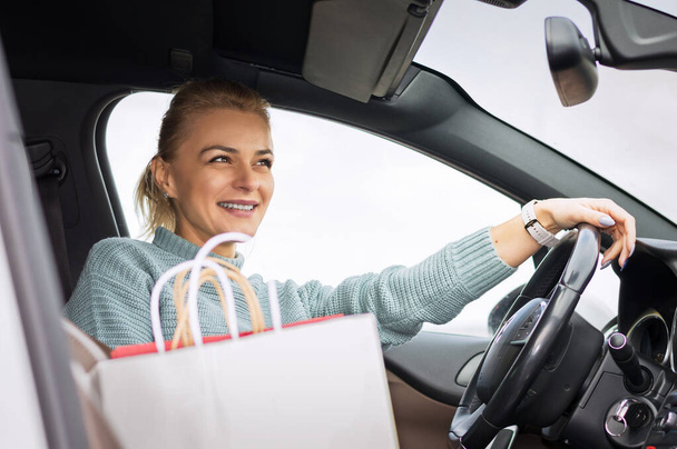 Élégante femme blonde avec ses sacs à provisions dans la voiture.Concept de shopping. - Photo, image