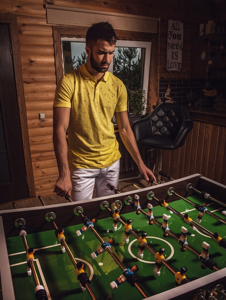 Молодой красивый мужчина в жёлтой футболке играет в футбол
. - Фото, изображение