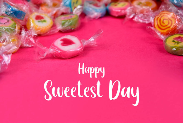Happy Sweetest Day stock images. Pile of colorful candies on a pink background. Candy with heart stock images - Photo, Image