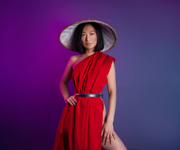 asian woman in red cape and asian hat posing on bright neon background - Foto, Imagem
