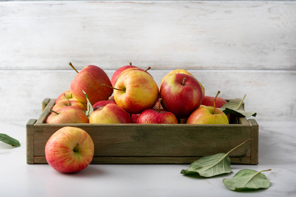 Harvest of ripe apple fruits in crate on light table - Foto, Imagem