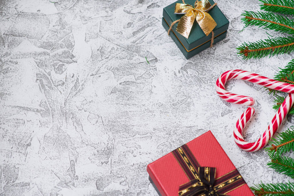 Noworoczna lub świąteczna kompozycja świerkowych zielonych gałęzi, prezentów noworocznych i lizaków bożonarodzeniowych na jasnym tle teksturalnym. Płaski układ, układ, przestrzeń do kopiowania - Zdjęcie, obraz