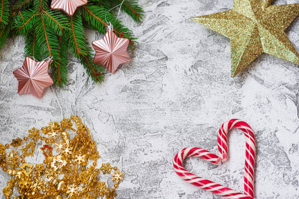 Πρωτοχρονιάτικη ή Χριστουγεννιάτικη σύνθεση από πρασινωπά κλαδιά ερυθρελάτης, γιρλάντα της Πρωτοχρονιάς, αστέρι και γλειφιτζούρια Christma σε ένα φωτεινό φόντο υφή. Επίπεδη διάταξη, διάταξη, αντιγραφή χώρου - Φωτογραφία, εικόνα