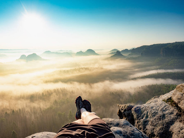Első ember kilátás a pihentető túrázó lábak, pihenés közben túrázás. Magas sziklák, tiszta ég és nap, - Fotó, kép