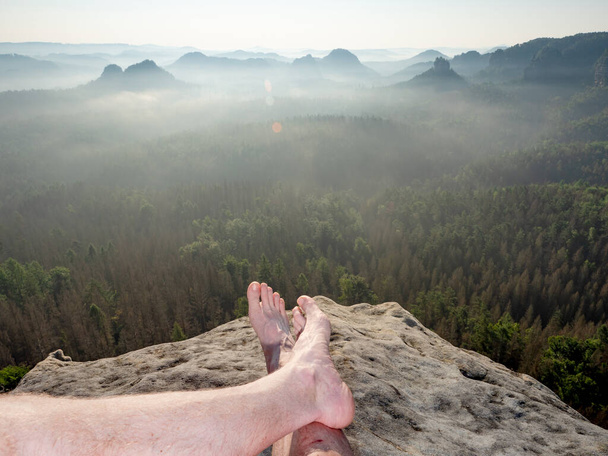 Álljon meg utazás közben, és pihenjen közel a sziklához a mély szurdok felett. Reggel köd az erdő felett a tájban. - Fotó, kép
