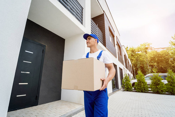 Young delivery man hold a cardboard box in his hands - Foto, Bild