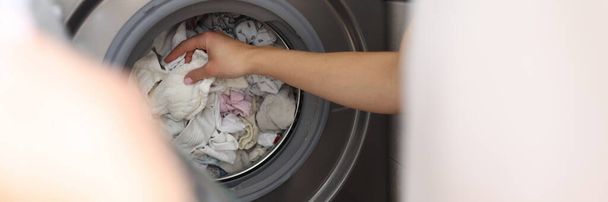 Женская рука вытаскивает чистое белье из стиральной машины крупным планом - Фото, изображение