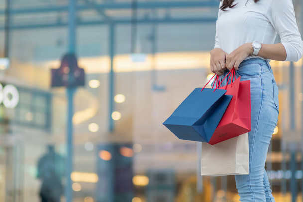 Молодая женщина, держащая сумку с покупками после похода по магазинам за скидками в универмаге по мере приближения новогодних праздников, начинает распродажу. торговая концепция - Фото, изображение