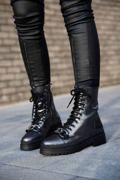 Vrouw in stijlvol lederen zwarte laarzen en jeans buiten. Close-up van vrouwelijke benen in de mode footwea - Foto, afbeelding
