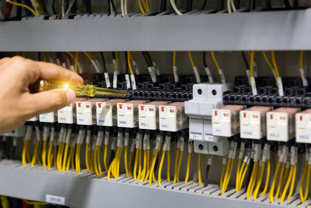 Sähkömiehet kädet testaus nykyinen sähkö ohjauspaneelissa. - Valokuva, kuva
