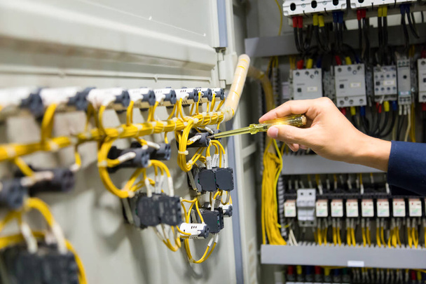 Eletricistas mãos testando corrente elétrica no painel de controle. - Foto, Imagem