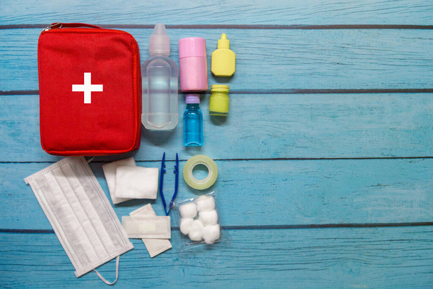 Vista superior bolsa de primeros auxilios niño con suministros médicos sobre fondo de madera. - Foto, imagen