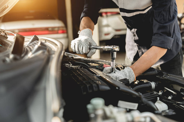 Autószerelő szerelő kezek javítás egy autó motor autóipari műhely egy csavarkulcs, autószerviz és karbantartás, javítási szolgáltatás. - Fotó, kép