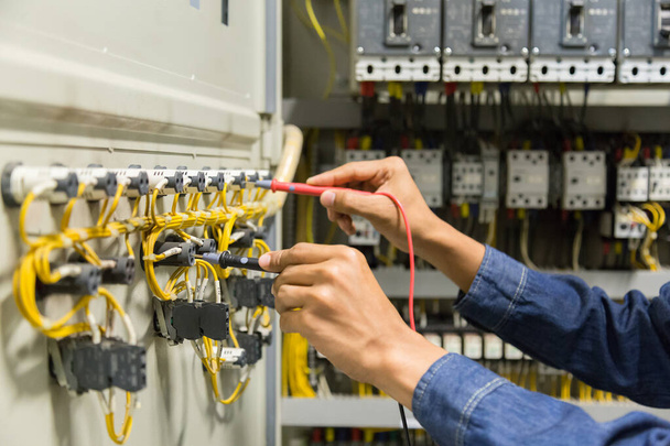 Probador de trabajo de ingeniero eléctrico que mide el voltaje y la corriente de la línea eléctrica de energía en el control del gabinete electico. - Foto, imagen
