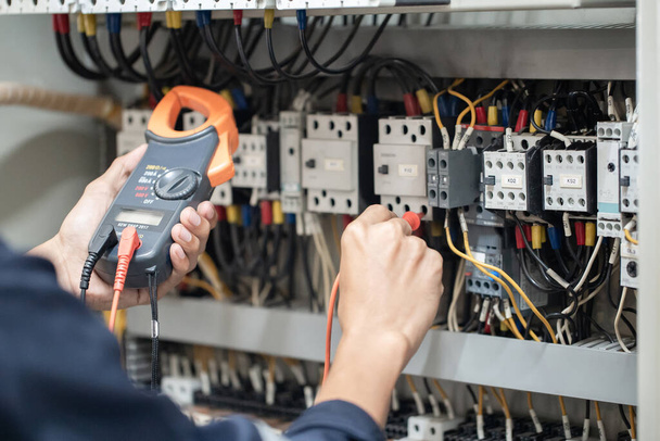 Testeur de travail ingénieur électricien mesurant la tension et le courant de la ligne électrique dans le contrôle de l'armoire électrique, contrôle de concept le fonctionnement du système électrique . - Photo, image