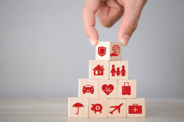 Hand arranging flips wood block stacking with icon insurance: car, real estate and property, travel, finances, health, family and life, insurance concept. - Photo, Image