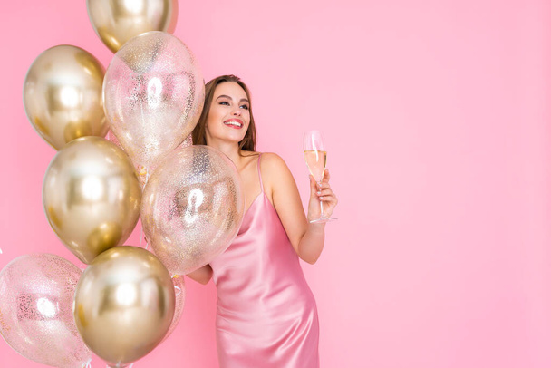 Smiling girl holds champagne, air balloons on colorful background. birthday new year holiday party.  - Fotografie, Obrázek