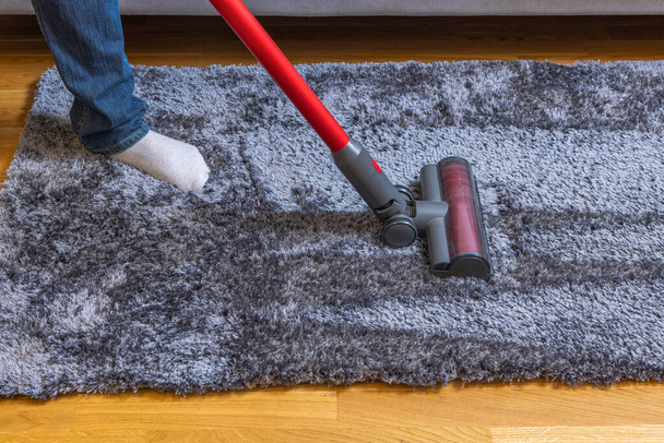 Close up view of man vacuum uming of carpet on parquet floor moment. Швеция.  - Фото, изображение