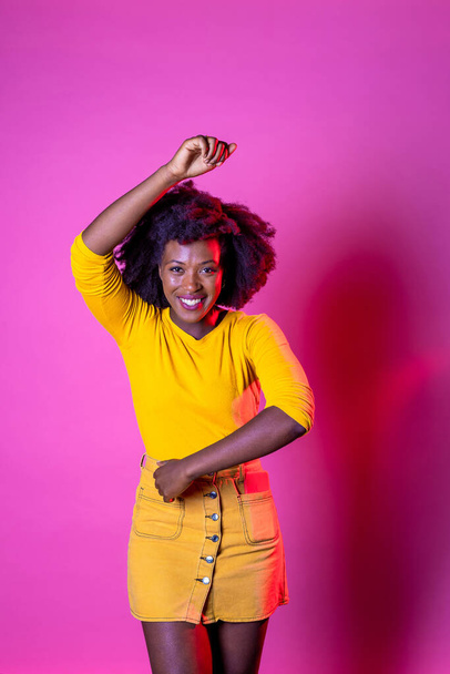 Jeune cheveux bouclés femme noire dansant souriant riant en s'amusant clubbing et faire la fête fond isolé - Photo, image